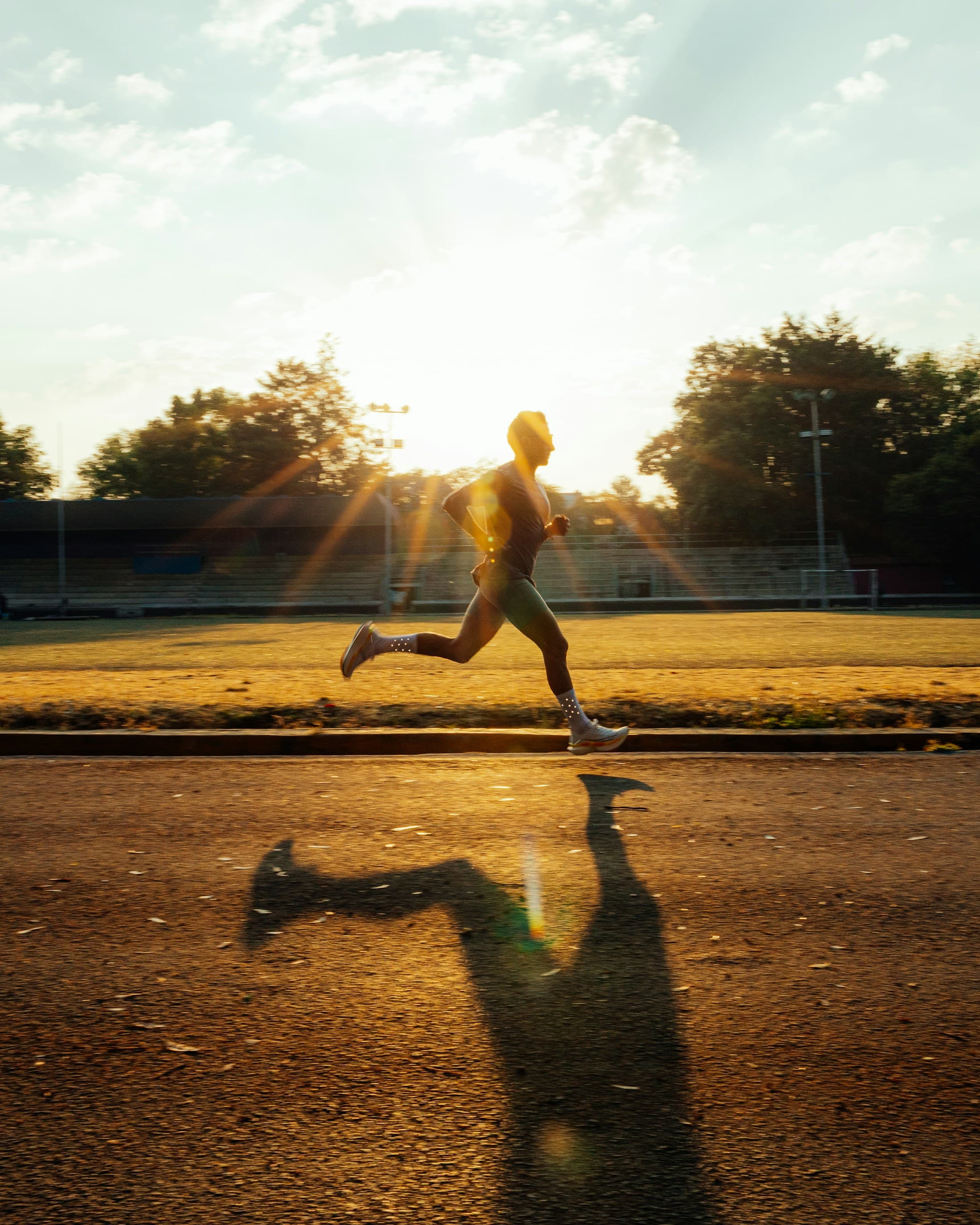 A runner training outdoors in early morning sunlight.